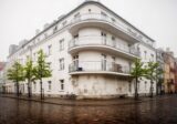 Narożnik modernistycznej kamienicy z zaokrąglonymi balkonami przy szerokiej ulicy, jak w przedwojennym śródmieściu Gdyni