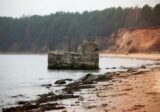 Betonowa ruina w płytkiej wodzie przy plaży pod klifem na północy Gdyni