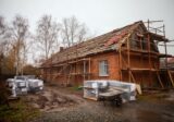 Stary ceglany dom w remoncie z rusztowaniem i odsłoniętą więźbą dachową